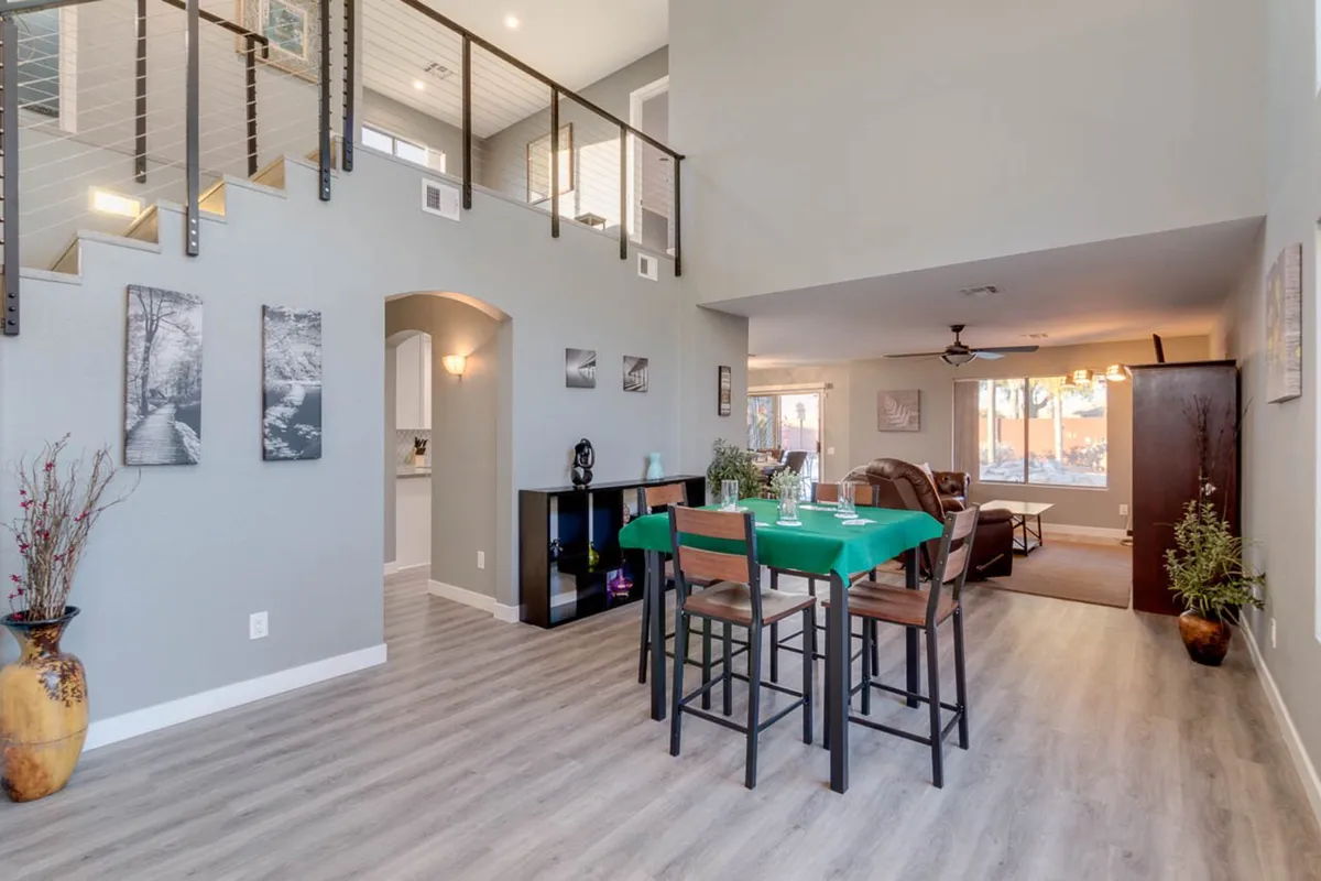 A spacious, warmly lit interior dining area with a large table and stylish staircase in the background. Artwork on the walls adds personality, and the atmosphere is lively and welcoming, ideal for group meals and socializing after a day of exploring.