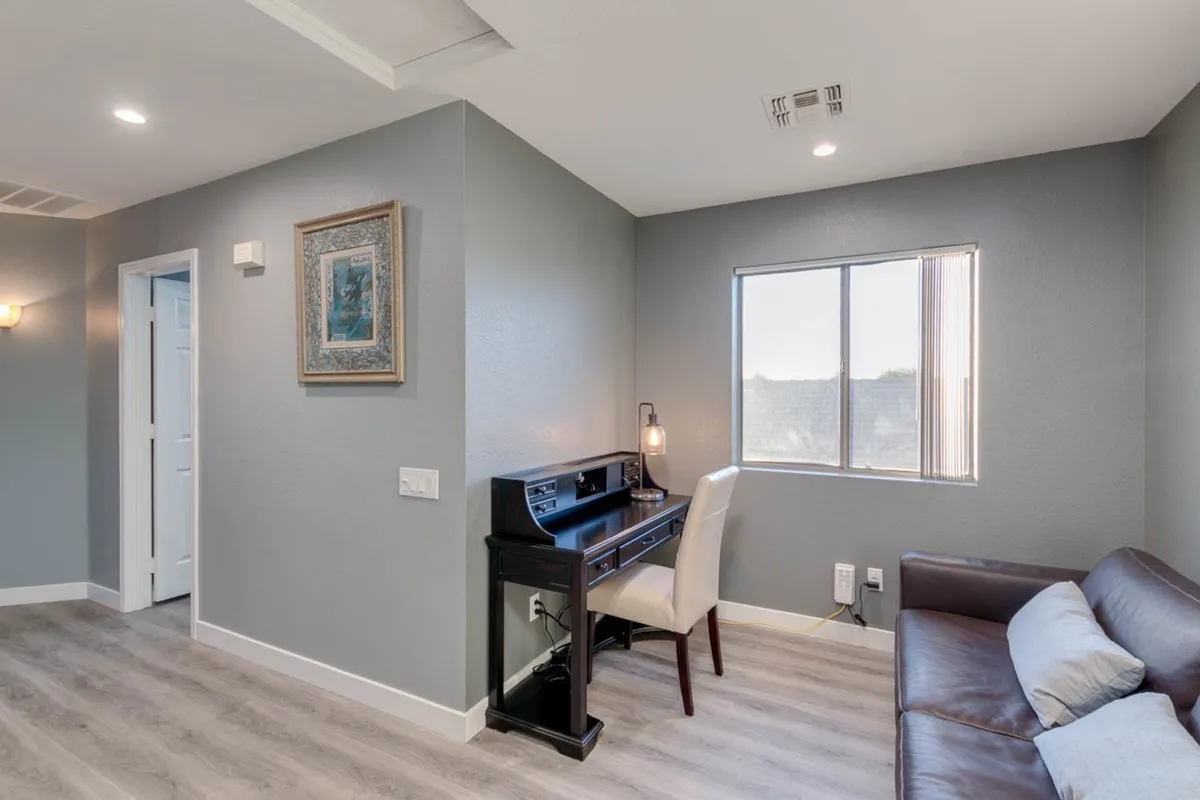 A tranquil lofted area with a piano, comfortable sofa, window providing natural light, and framed artwork on the wall. The scene is ideal for reading, working, or relaxing, evoking a peaceful and productive environment.