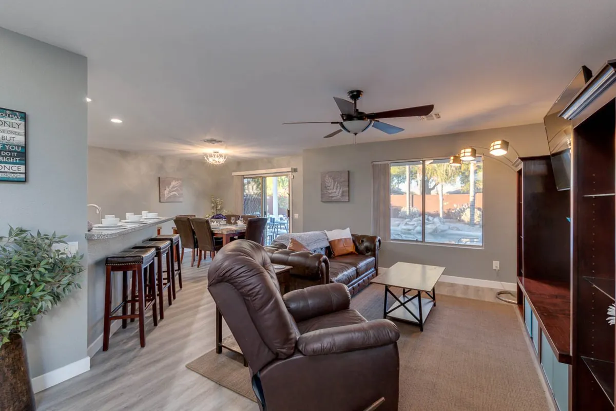 This image features a spacious, sunlit living area with comfortable leather sofas, a dining area, and large windows that flood the space with natural light. The layout is open and inviting, perfect for relaxation and group gatherings.