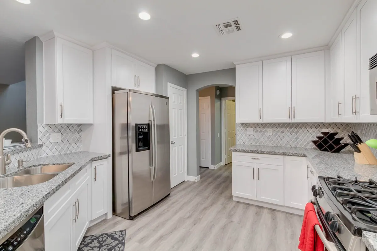 A welcoming, modern kitchen featuring stainless steel appliances, granite countertops, sleek cabinetry, and a spacious island that invites group meal preparation. The open layout suggests easy access to adjacent living or dining areas, reinforcing the space as the heart of the home for gathering and entertaining.